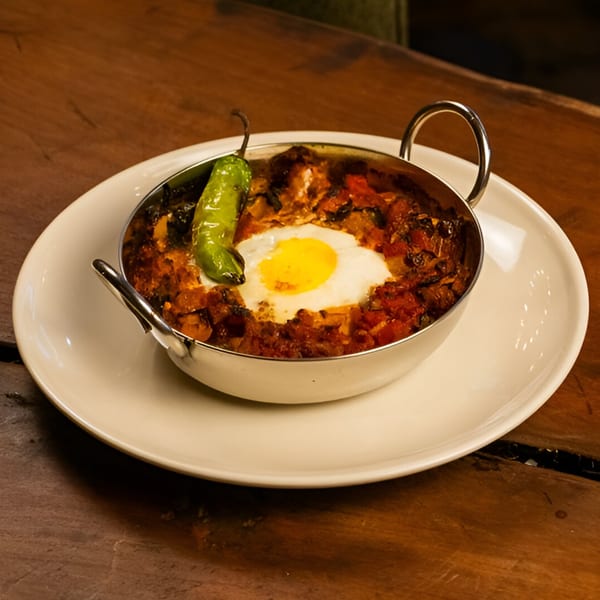 Starlite Restaurant's shakshuka with a fried egg and green pepper in a metal skillet.