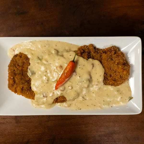 Starlite Restaurant's chicken fried steak with creamy gravy and a red chili pepper on a white plate.