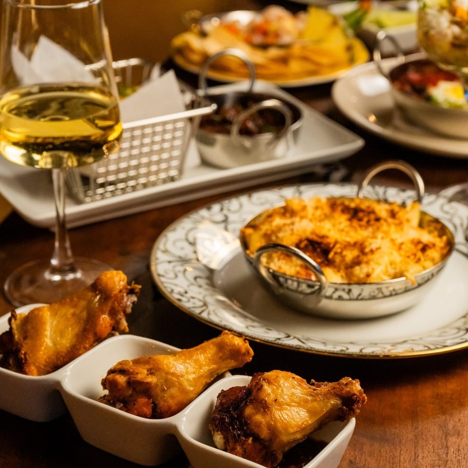 Starlite Restaurant and Bar's mac and cheese, chicken wings, and white wine on a wooden table.