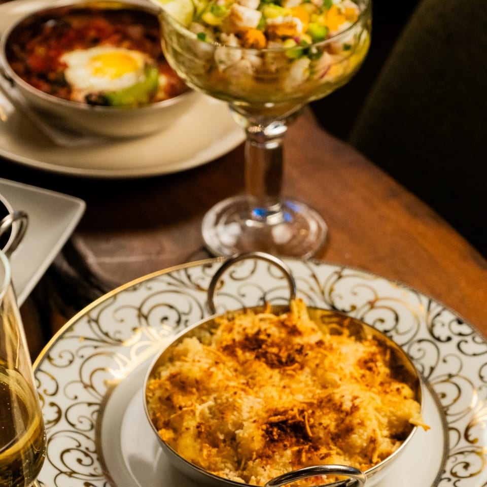 Starlite Restaurant's mac and cheese, chili with egg, and a seafood cocktail on a wooden table.